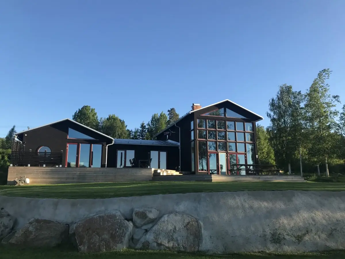 Färdig mörk träbyggnad med glasad gavel och stort trädäck.