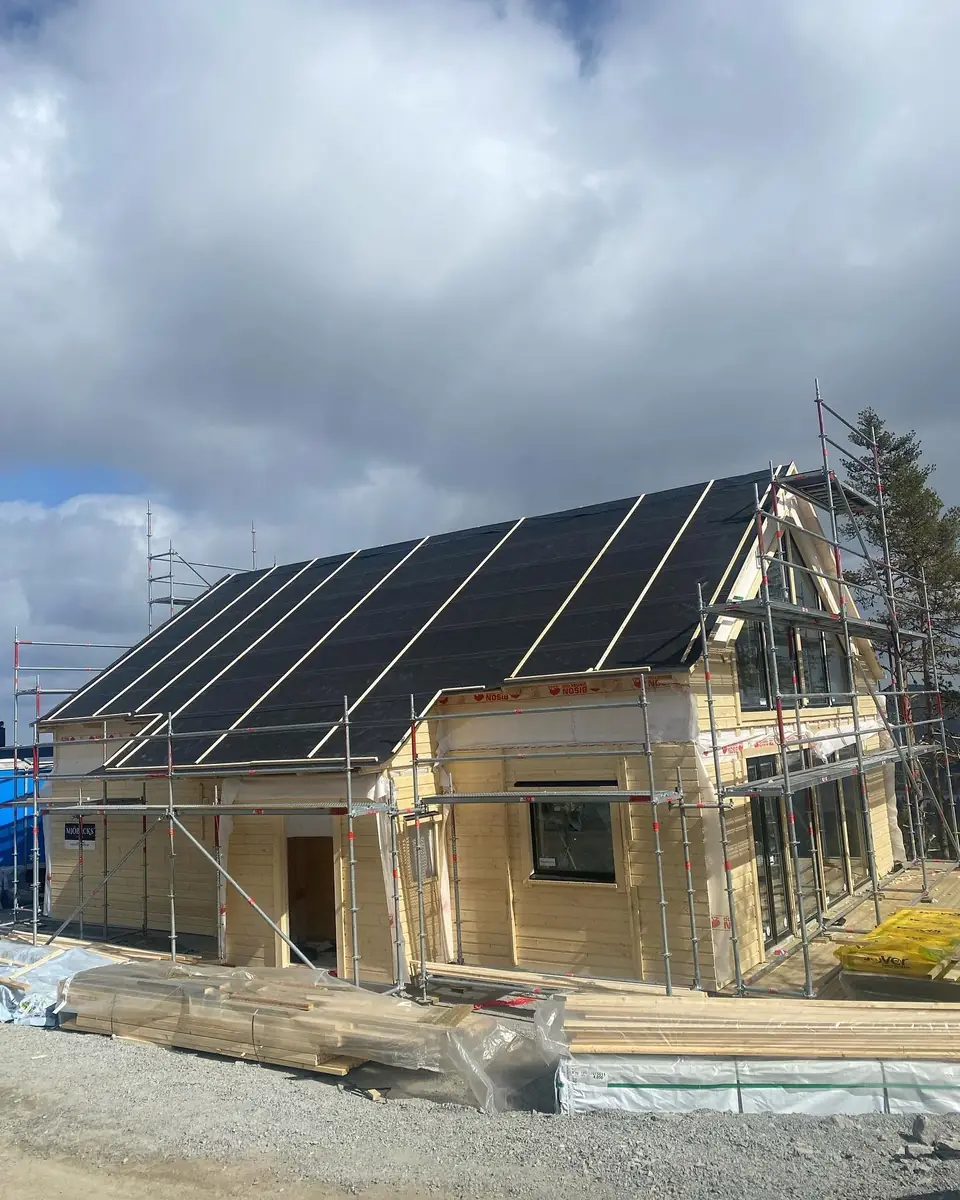 Nybyggt trähus med takpapp, läkt och byggställning.