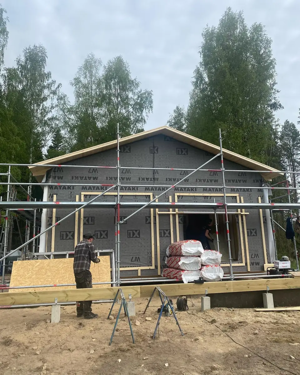Tillbyggnad på trähus med vindskydd och byggställning.