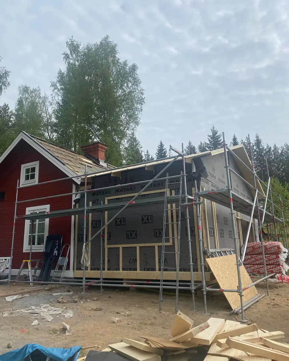 Tillbyggnad ansluten till ett rött trähus med byggställning.