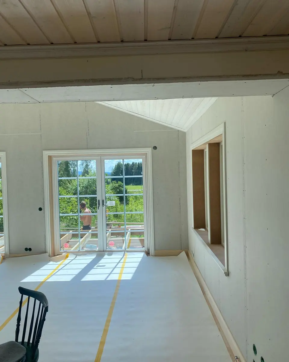 Invändigt rum under färdigställande med glasade dubbeldörrar.