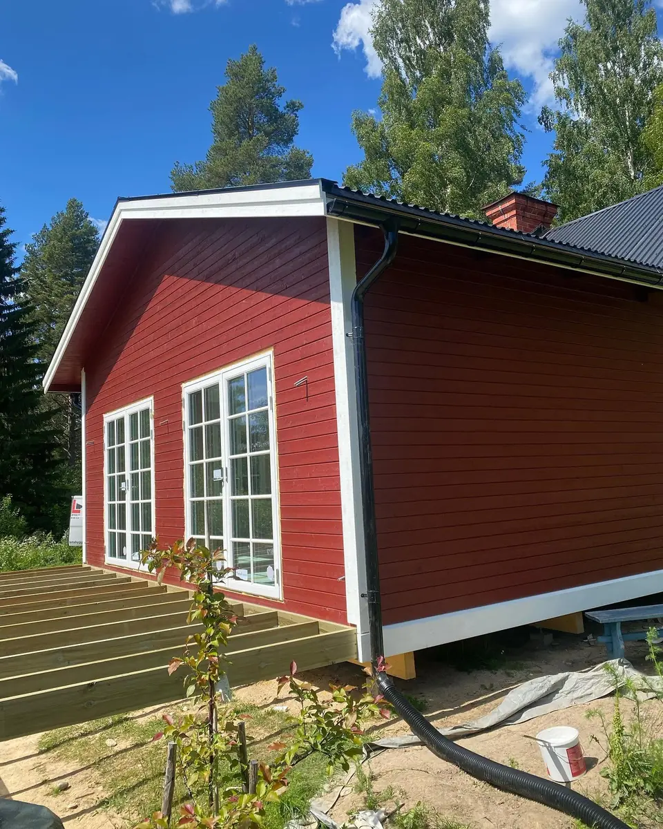 Färdig röd tillbyggnad med vita foder och stora fönster.
